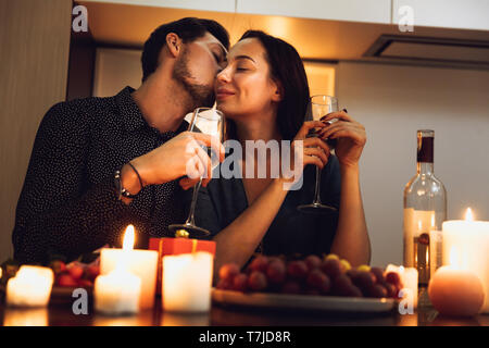 Schöne leidenschaftliche Paar in ein romantisches Abendessen bei Kerzenlicht zu Hause, Wein trinken, Toasten Stockfoto