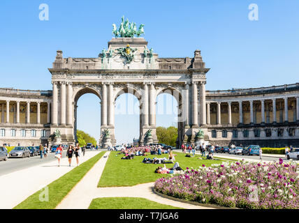 Die Menschen genießen Sie einen sonnigen Tag am Fuße des Arcade du Cinquantenaire, die monumentale triple Arch im Cinquantenaire-Park in Brüssel, Belgien. Stockfoto