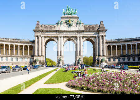 Die Menschen genießen Sie einen sonnigen Tag am Fuße des Arcade du Cinquantenaire, die monumentale triple Arch im Cinquantenaire-Park in Brüssel, Belgien. Stockfoto