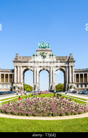 Die Arcade du Cinquantenaire, der Triumphbogen im Cinquantenaire-Park in Brüssel, Belgien, an einem sonnigen Tag mit ein Blumenbeet im Vordergrund. Stockfoto