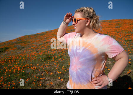 Frau mit blonden geflochtene Haar schaut in die Ferne im Mohnfeld bei einem super Blüte Stockfoto