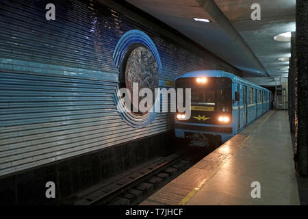 Ein Zug fährt in die U-Bahnstation Kosmonavtlar ein, die in der Sowjetzeit gebaut wurde und den Kosmonauten der Sowjetunion in der Hauptstadt Taschkent in Usbekistan gewidmet ist. Die in der ehemaligen UdSSR erbaute Taschkent Metro ist eines von nur zwei U-Bahnsystemen, die derzeit in Zentralasien betrieben werden und deren Stationen zu den kunstvoll verzierten der Welt gehören. Stockfoto