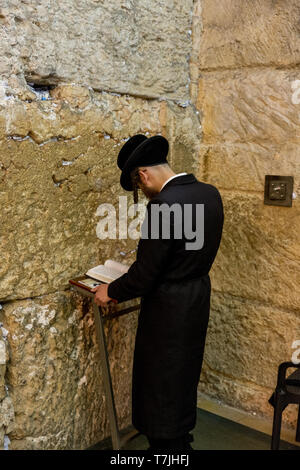 Jüdischer Mann betet neben einen Riss voller Briefe mit schriftlichen Gebet an der Klagemauer in Jerusalem. Israel Stockfoto