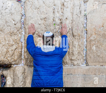 Jerusalem, Israel, 27-März-2019: jüdische Mensch betet in Blau mit keppel mit David Kreuz neben einen Riss, gefüllt mit Briefe mit schriftlichen Gebete bei Stockfoto