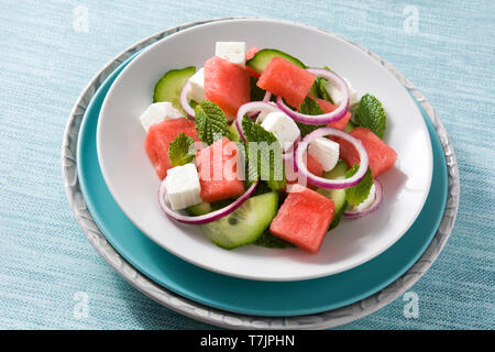 Wassermelonen Salat mit Feta Käse, Minze, Zwiebel und Gurke auf blauem Hintergrund Stockfoto