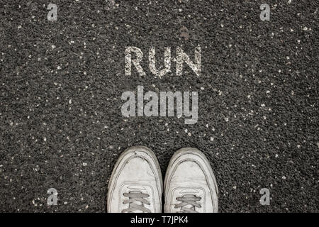 Neues Leben Konzept, Sport Schuhe und das Wort laufen auf Asphalt Boden geschrieben, Motivations Slogan. Stockfoto