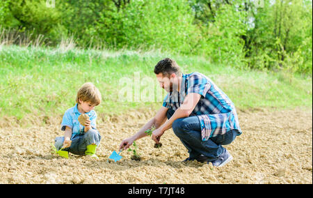 Reichen natürlichen Boden. Eco Farm. happy Earth Day. Stammbaum. neues Leben. Böden und Düngemitteln. kleiner Junge Kind helfen Vater in der Landwirtschaft. Vater und Sohn Blumen Pflanzen im Boden. Tag der Erde. Garten Bett. Stockfoto