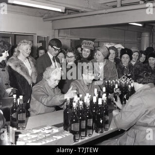 1960, historische, eine Gruppe von MIDDEL-alter liebe Kolleginnen, viele in ihre Hüte und Pelzmäntel, versammeln sich zu einem Apéro als Flaschen Scotch Whisky auf einen Zähler, England, UK festgelegt sind. Stockfoto