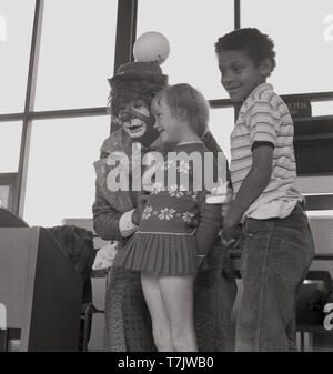 1960, historische, einem Zirkus Clown Besuch einer Grundschule, auf der Bühne mit zwei jungen Schüler, South London, England, UK. Stockfoto