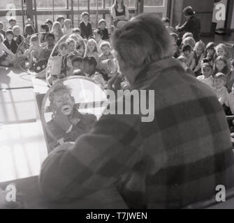 1960, historische, einem Zirkus Clown innerhalb einer Stufe in einer Schule Aula sein Gesicht vorbereiten, South London, England, UK. Stockfoto