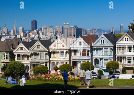 San Francisco, CA, USA - 20. Juli 2011: viktorianische Häuser in San Francisco mit der Innenstadt im Hintergrund. Blick vom Alamo Square bei Dämmerung, San Fran Stockfoto