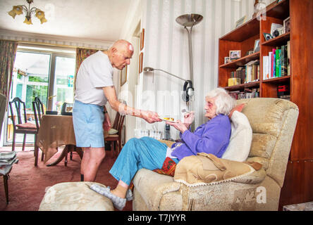 93 Jahre alter Mann mit Herz Zustand sorgt durch seine stark Sehbehinderte 90 Jahre alte Frau und Köche, prepaeres Mahlzeiten und die Hausarbeit für Sie. Stockfoto