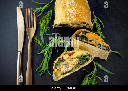 Strudel mit Fisch und Spinat auf schwarzem Hintergrund Stockfoto