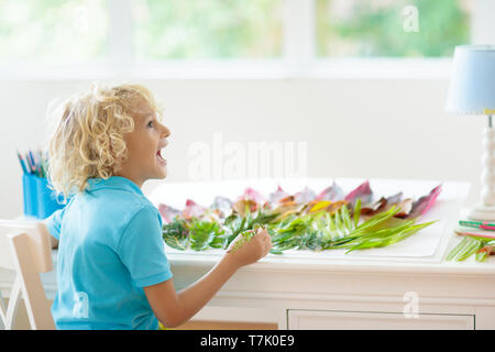 Kind erstellen Bild mit bunten Blättern. Kunst und Handwerk für Kinder. Little Boy, collage Bild mit Regenbogen pflanze Blatt. Biologie Hausaufgaben für Yo Stockfoto