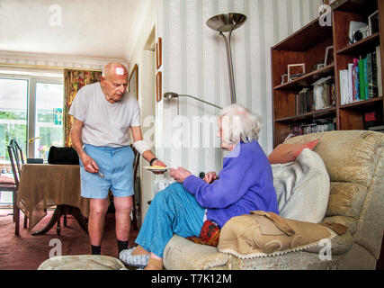 93 Jahre alter Mann mit Herz Zustand sorgt durch seine stark Sehbehinderte 90 Jahre alte Frau und Köche, prepaeres Mahlzeiten und die Hausarbeit für Sie. Stockfoto