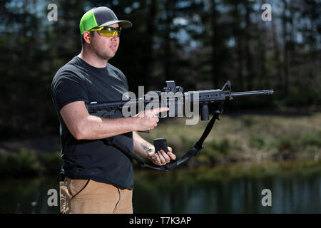 Ein Mann mit einem modernen sportlichen Gewehr in der einen Hand und das Magazin in der anderen Hand. Stockfoto