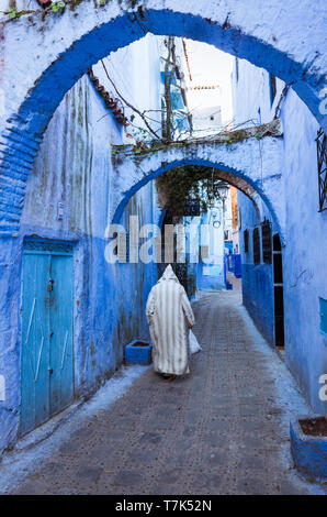 Chefchaouen, Marokko: ein älterer Mann mit einem traditionellen djellaba Spaziergänge im blau getünchten Gassen der Medina, der Altstadt. Stockfoto