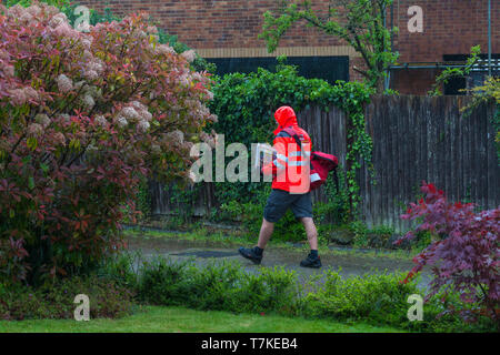 Ashford, Kent, Großbritannien. 8. Mai, 2019. UK Wetter: Die Aussichten für den Tag ist heavy rain mit maximalen Temperaturen von 12 °C, helleres Wetter wird später an diesem Abend erwartet. Ein Postmitarbeiter geht über sein Geschäft die Briefzustellung trotz der schrecklichen Bedingungen. © Paul Lawrenson 2019, Foto: Paul Lawrenson/Alamy leben Nachrichten Stockfoto