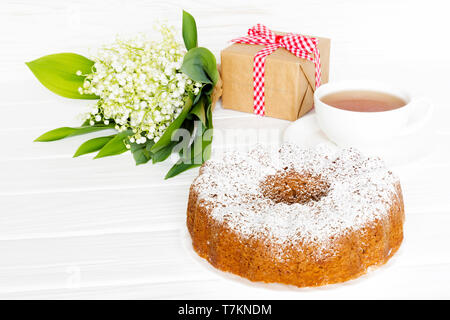 Stillleben mit Bundt Kuchen, Kaffee und Blumen mit Geschenk. Gruß Konzept Stockfoto