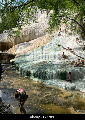 Bagni San Filippo, Italien - 24 April 2019: Menschen Ruhe auf den thermischen Salz Wasserfälle der Mineralquellen von Bagni San Filippo an einem sonnigen Tag. Stockfoto