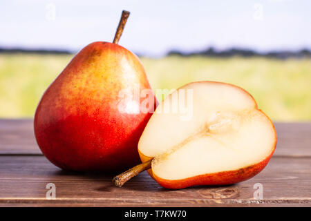 Gruppe von einer ganzen Hälfte der Frische rote Birne mit grünen Weizenfeld Stockfoto