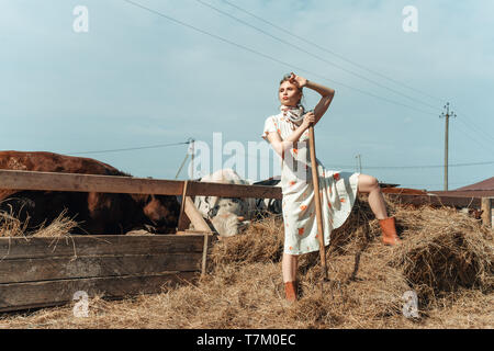 Eine schöne Frau auf einem Bauernhof Feeds das Vieh mit Heu Stockfoto