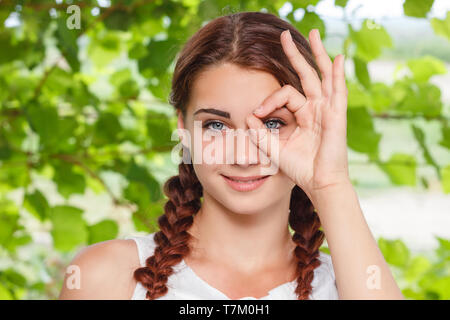 Freundlich lächelnde Mädchen zeigt Geste alles OK in der Natur Stockfoto