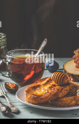 Gesundes Frühstück Konzept. French Toast mit Honig, Früchte und Tee über weiß Holz- Hintergrund Stockfoto
