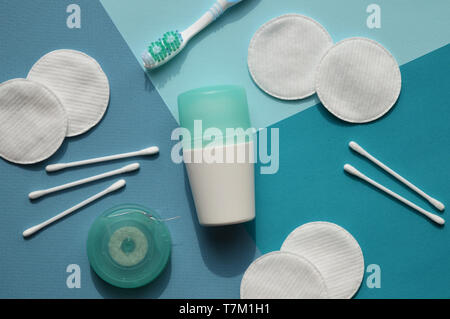 Wattestäbchen und Pads auf blauem Hintergrund. Ein Deodorant mit Deckung der türkise Farbe, Zahnbürste und Zahnseide. Stockfoto