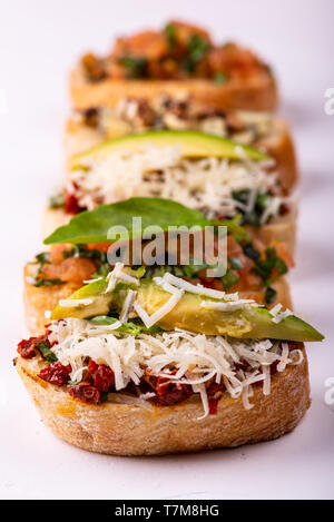 Einstellen der sortierten Bruschetta mit verschiedenen Toppings für Urlaub auf weißem Hintergrund. Makro. Party Food Konzept. Stockfoto