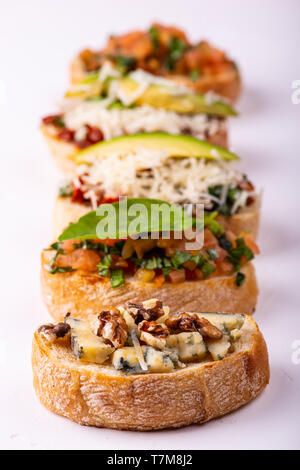 Vielzahl von canape mit Hummus, Tomate, Avocado, Käse, Nussbaum und frisches Gemüse auf weißem Hintergrund. Blick von oben auf die gesunden Snack Konzept. Stockfoto