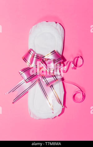 A Sanitary Pads mit Band auf der rosa Hintergrund gebunden. Medizin, Gesundheit von Frauen und die ovulation Konzept. Stockfoto