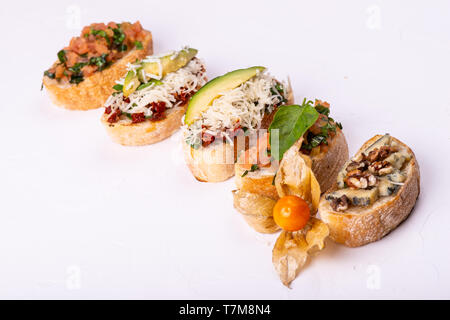 Vielzahl von canape mit Hummus, Tomate, Avocado, Käse, Nussbaum und frisches Gemüse auf weißem Hintergrund. Blick von oben auf die gesunden Snack Konzept. Stockfoto