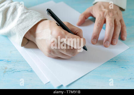 Ein Stift in der Hand eines Mannes. Weißes Blatt Papier. Signieren eines Dokuments. Stockfoto