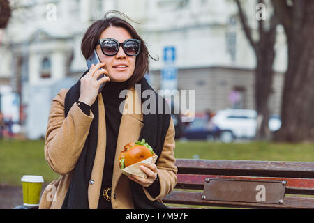 Junge Schönheit Business woman Essen fast food und Arbeiten am Telefon während der Sitzung im City Bank Stockfoto