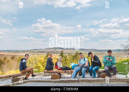 Eine Gruppe von Freunden mit Kindern sitzen auf holzbank Landschaft mit schöner Aussicht. Stockfoto
