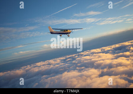 Kleinen einmotorigen Flugzeug fliegen in den wunderschönen Sonnenuntergang Himmel durch das Meer der Wolken Stockfoto