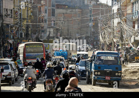 Ein Gewirr von Fahrzeugen und elektrischen Drähten auf einer staubigen Straße in Kathmandu, Nepal Stockfoto