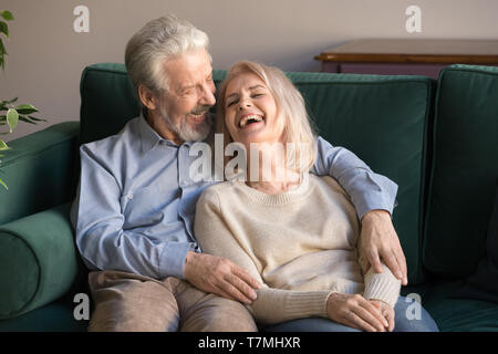 Lieben Mann im mittleren Alter, die lachende Frau, sitzen auf der Couch Stockfoto