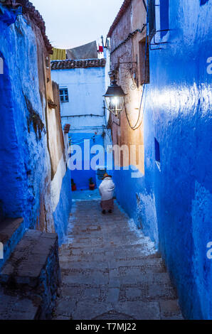 Chefchaouen, Marokko: Ein älterer Riffian Frau Spaziergänge entlang einer blau getünchten Gasse in der Medina, der Altstadt. Stockfoto