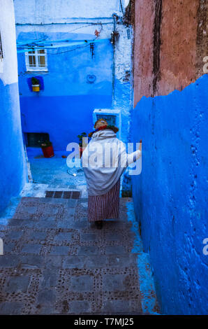 Chefchaouen, Marokko: Ein älterer Riffian Frau Spaziergänge entlang einer blau getünchten Gasse in der Medina, der Altstadt. Stockfoto