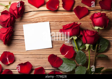 Rote Rosen mit weissem Papier auf Holz- Hintergrund Stockfoto