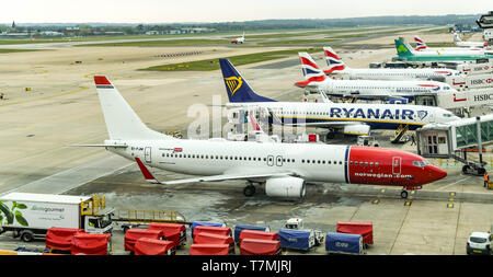 Der Flughafen London Gatwick, ENGLAND - April 2019: Boeing 737 von Norwegischen und andere Jets bis am Flughafen London Gatwick gesäumt betrieben Stockfoto