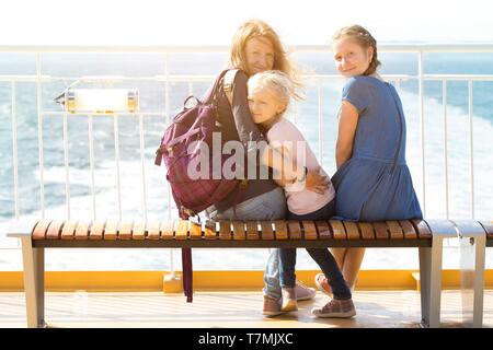Familie - Mutter und zwei Töchtern auf einer Bank sitzen auf der Fähre und das Meer im Hintergrund Stockfoto