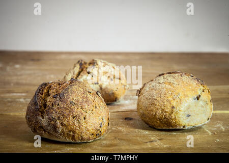 Drei kleine Laibe von französischem Brot auf Anzeige auf einem rustikalen Holztisch, Baguette Stil. Sie sind in französischer Sprache petits Schmerzen genannt, aus Hefe namens Le Stockfoto
