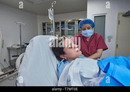 Krankenschwester hilft Patienten in der Chirurgie auf Klinik Hintergrund Stockfoto