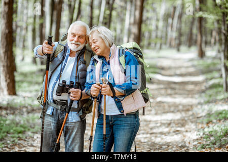 Schönes älteres Paar wandern mit Rucksack und Trekking Stöcke im Wald. Konzept der aktiven Lebensstil im Ruhestand Stockfoto