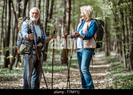 Schönes älteres Paar wandern mit Rucksack und Trekking Stöcke im Wald. Konzept der aktiven Lebensstil im Ruhestand Stockfoto