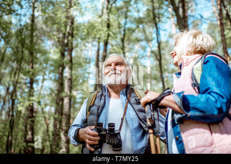 Senior paar Suche mit dem Fernglas beim Wandern im Wald. Konzept eines aktiven Lebensstils auf Ruhestand Stockfoto