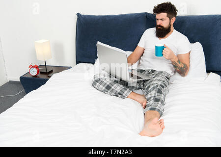 Schnell am Morgen unterhalten. Eine Pause. Zu viel Arbeit. All seine Energie zu arbeiten. Geschäftsmann mit Computer. bärtiger Mann Arbeiten am Laptop. Mann im Schlafzimmer Kaffee trinken. Energie und Müdigkeit. Stockfoto